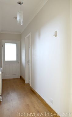 an empty hallway with white walls and wood flooring is pictured in this image from the front door