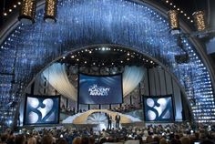 the stage is lit up with chandeliers and people standing on it in front of them