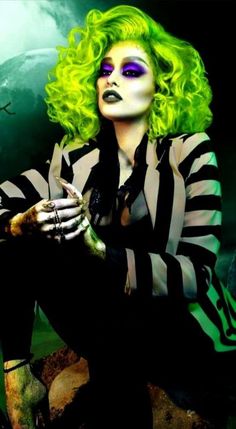 a woman with green hair and makeup is dressed in black and white striped clothing, holding her hands on her knees