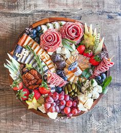 a wooden platter filled with different types of meats, cheeses and fruit