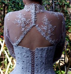 the back of a woman's wedding dress, with flowers on it and lace detailing