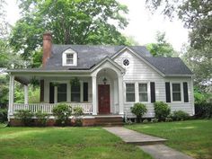 a white house with black shutters and red door