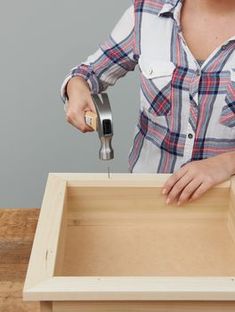 a woman is using a tool to cut out the bottom part of a wooden box