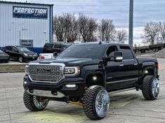 a black truck parked in front of a building with its lights on and tires off