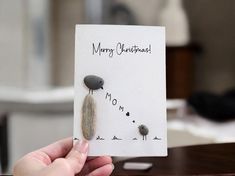 a person holding up a christmas card with rocks on it and the words merry christmas