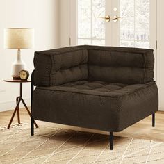 a brown couch sitting on top of a wooden floor next to a table with a lamp