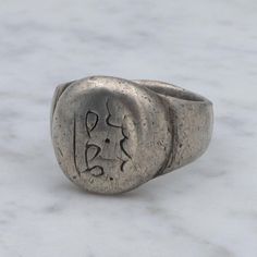 This ancient Middle Eastern silver ring features a simple signet designed head with engravings.  Measurements - size 9, weighs 14.1 grams, head 16mm wide, band base 8mm  Condition - good antique condition with surface wear  Markings - not marked but has been tested and is guaranteed Silver Antique Signet Ring, Vintage Oxidized Signet Ring For Gift, Vintage Silver Signet Ring With Oxidized Finish, Symbolic Silver Signet Ring With Oxidized Finish, Vintage Silver Oxidized Signet Ring, Silver Signet Ring, Middle Eastern, Signet Ring, Rings Statement