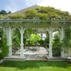 an outdoor gazebo with chairs and tables surrounded by greenery on either side of it