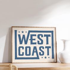 a blue and white sign sitting on top of a wooden shelf next to a vase