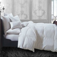 a bed with white comforters and pillows on it