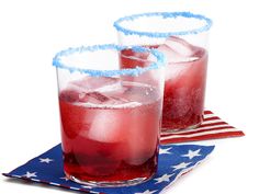 two glasses filled with red, white and blue drinks on top of a flag napkin