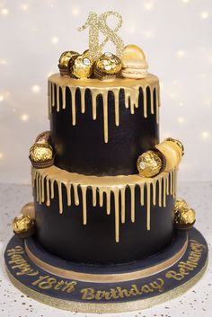 a black and gold birthday cake with icing dripping down the side on a table