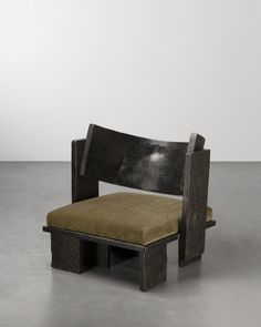 a wooden bench sitting on top of a cement floor next to a white wall in an empty room