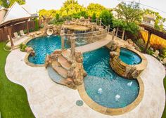 an outdoor swimming pool surrounded by rocks and water features a slide that leads to a waterfall