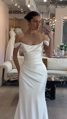 a woman in a white wedding dress taking a selfie with her cell phone while standing in front of a mirror