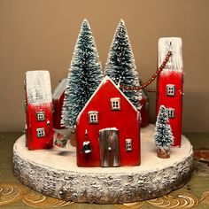 a small red house with trees and lights on the front is sitting on a table