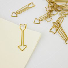 a bunch of paper clips sitting on top of a white table next to a piece of paper