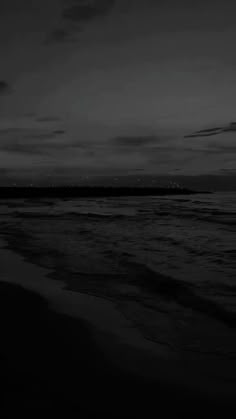 a black and white photo of the ocean at night