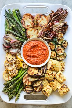 grilled vegetables on a platter with marinara sauce and asparagus for garnish