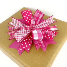 a present wrapped in brown paper with pink and white polka dots on the bow is sitting on top of a cardboard box