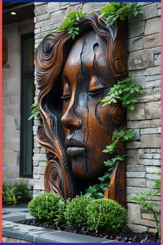 an artistic sculpture in the shape of a woman's face surrounded by greenery