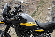 a black and yellow motorcycle parked in front of a mountain