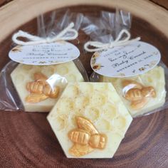 three bees soaps wrapped in cellophane on top of a wooden plate with tags