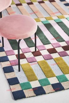 a pink chair sitting on top of a colorful rug