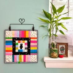 a potted plant sitting on top of a window sill next to a colorful quilt