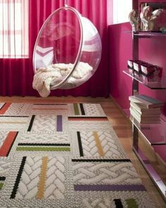 a room with pink walls and a hanging chair on the floor in front of a window