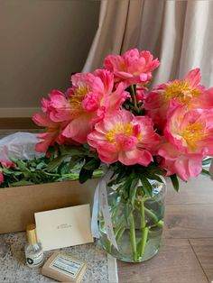 pink flowers are in a vase on a table next to a note and some other items