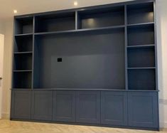 an empty bookcase in the middle of a room with wood floors and white walls