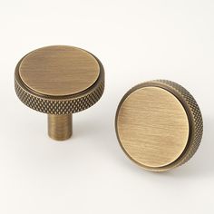 two brass knobs on a white background with no one in the photo looking at them