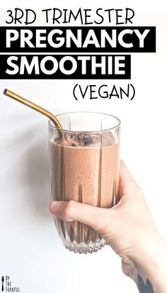 a hand holding a glass with smoothie in it and the words, 3d timester pregancy smoothie vegan