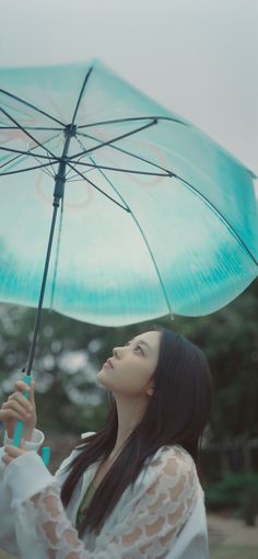 a woman is holding an umbrella in the air and looking up at something she's holding