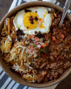 a bowl filled with rice, meat and an egg sitting on top of a table