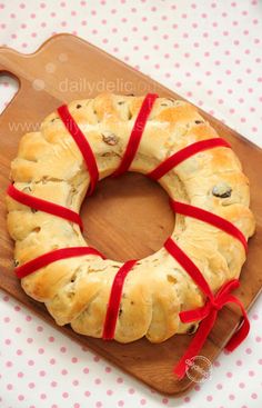 a piece of bread wrapped in red ribbon sitting on top of a wooden cutting board