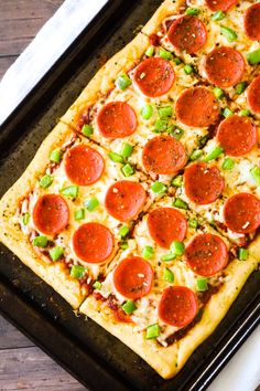 a square pizza with pepperoni and green onions