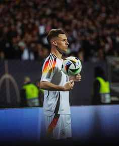 a man holding a soccer ball on top of a field in front of a crowd