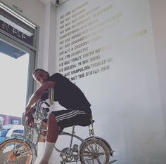 a man riding a bike in front of a wall with words written on the side