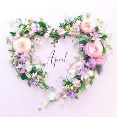 a heart shaped wreath with flowers and the word april written in it's center