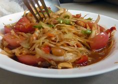 a white plate topped with lots of food and a fork sticking out of the bowl