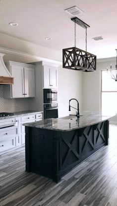 a large kitchen with an island in the middle and two pendant lights hanging from the ceiling