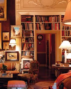 a living room filled with lots of furniture and bookshelves covered in pictures on the walls