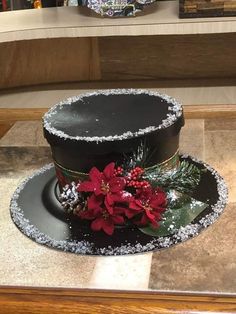 a black hat with poinsettis and snow on the top sitting on a table