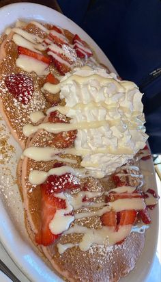 a white plate topped with pancakes covered in icing and strawberries