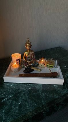 there is a tray with candles and a buddha statue on it