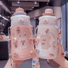 two small bottles with cartoon characters on them, one is pink and the other is white