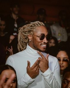 a man with dreadlocks standing in front of a group of people wearing sunglasses