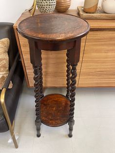 a small wooden table sitting on top of a white floor next to a black chair